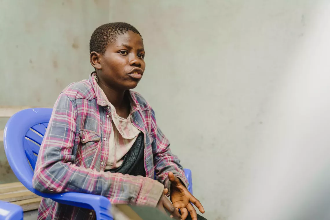 Une jeune fille parle, en &eacute;tant assise sur un chaise plastique