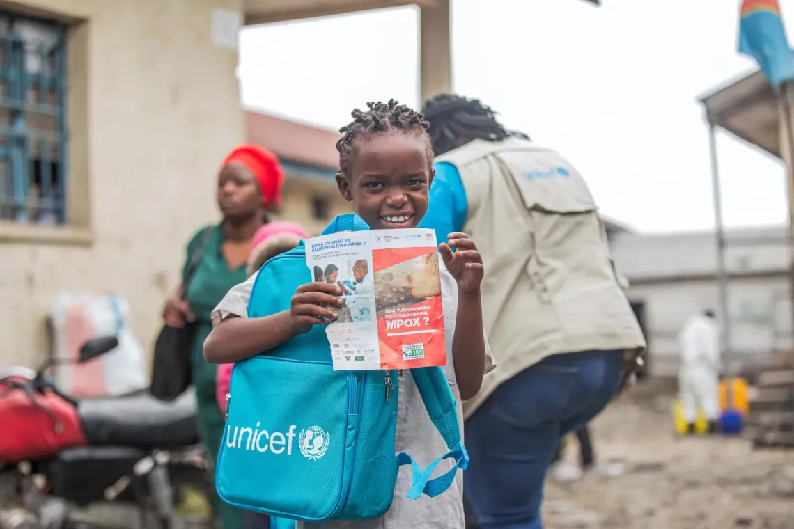 Une &eacute;coli&egrave;re portant un cartable et tenant une brochure de sensibilisation mpox