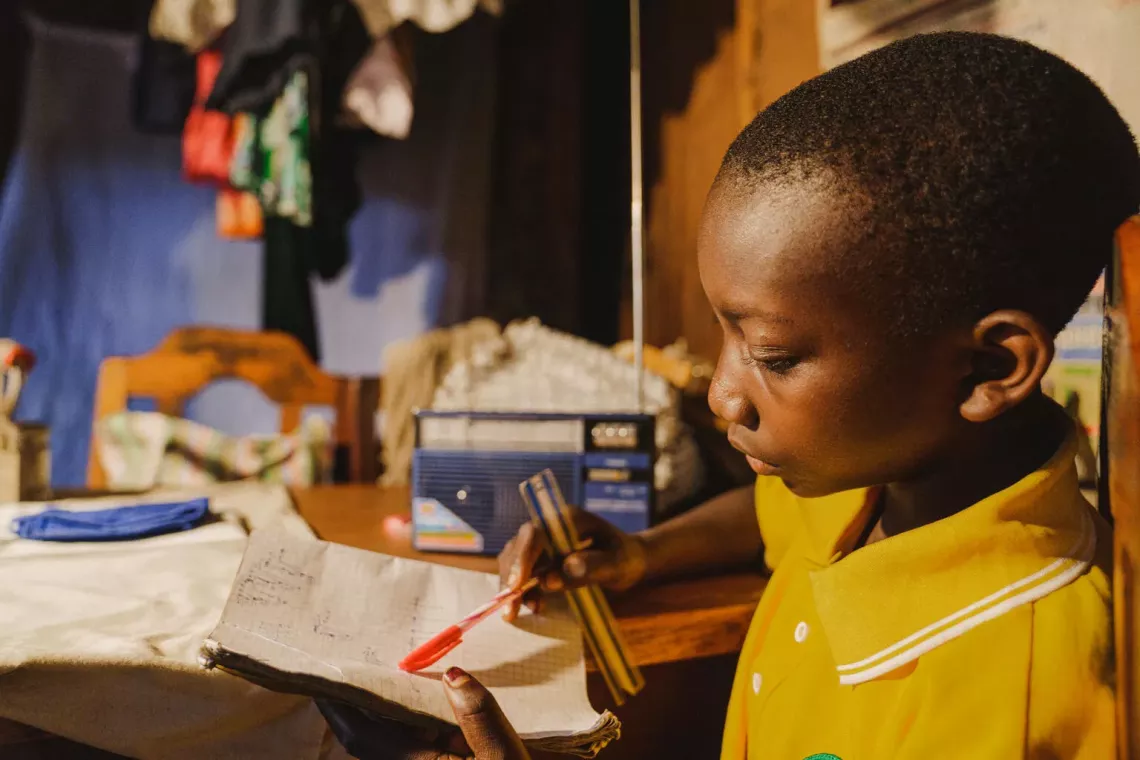 Her radio beside her, Amini, 12, revises under the supervision of her mother and her big sister 