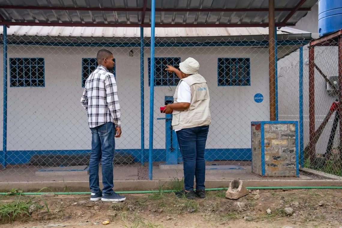 Deux personnes, dont une coll&egrave;gue de l'UNICEF, se tiennent devant une zone de traitement de d&eacute;chets
