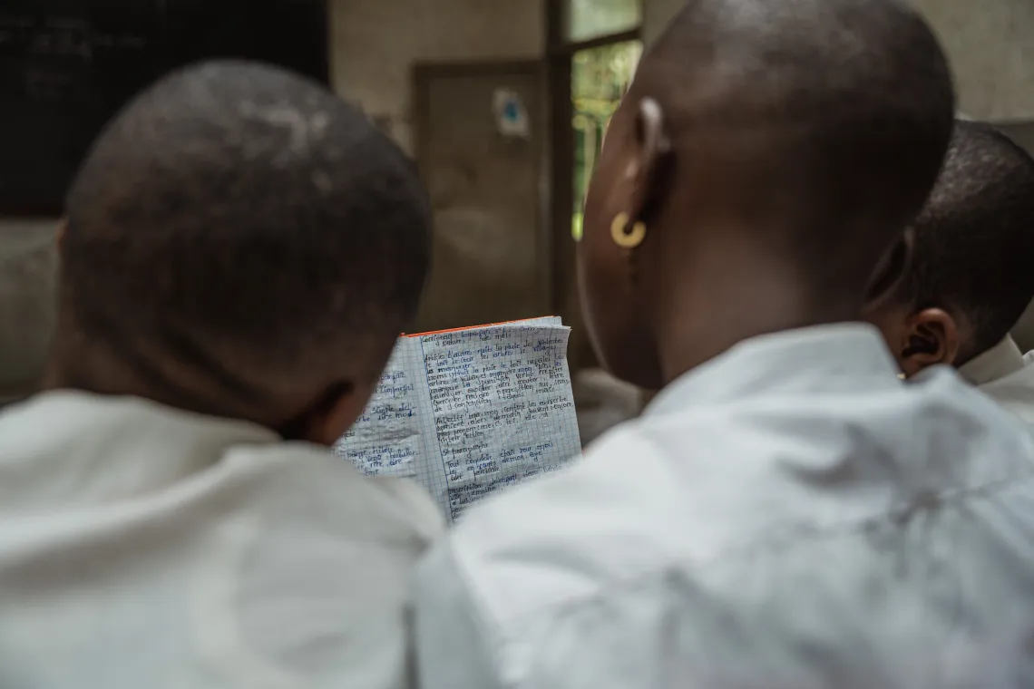 Trois &eacute;l&egrave;ves regardent un cahier