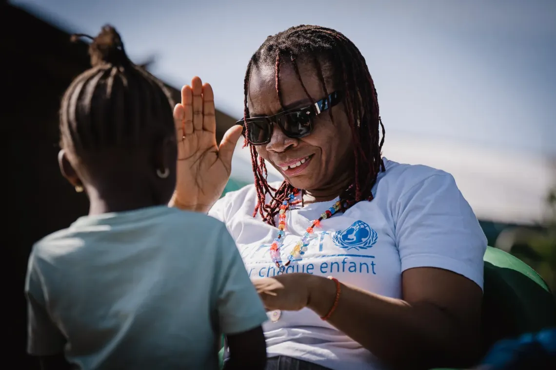 DRC. A UNICEF Education Officer plays with Grace in front of her home.