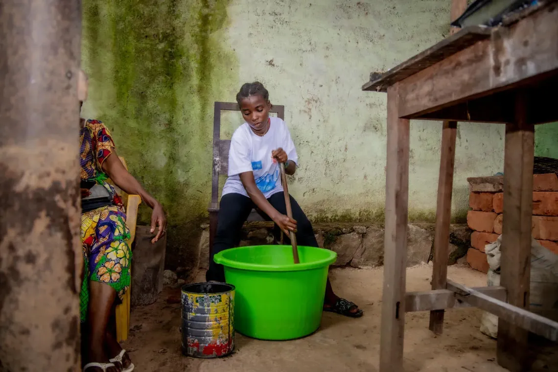 Une adolescente m&eacute;lange une mixture de savon dans une bassine verte
