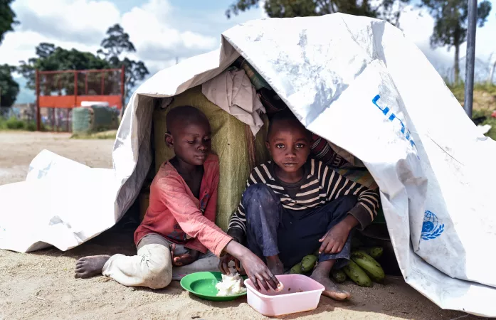 Deux enfants d&eacute;plac&eacute;s qui mangent dans leur abris