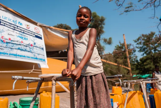 A girl standing at a water tap