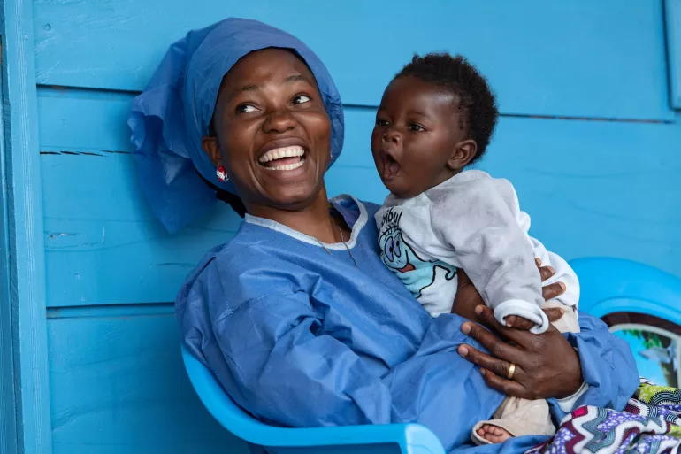 Une survivante d'Ebola tenant dans ses bras un enfant séparé de ses parents à cause de la maladie