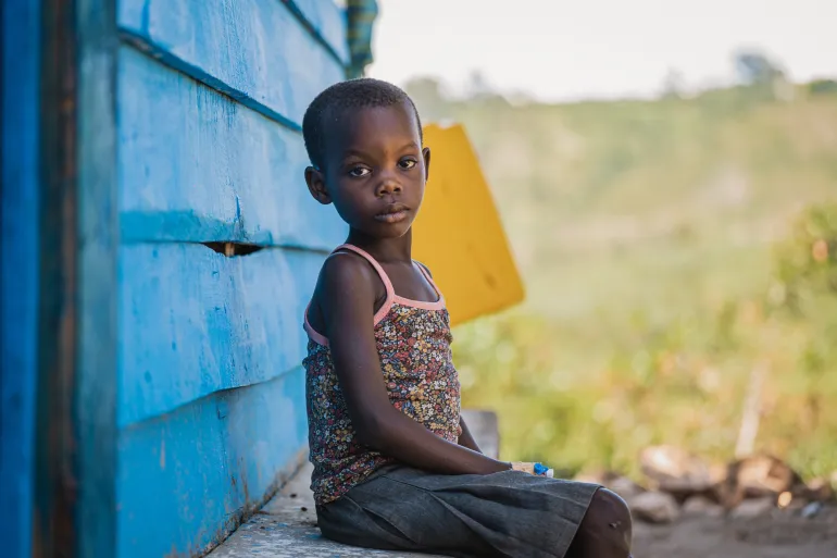 Une fille assise sur un banc de bas devant une structure en bois bleu