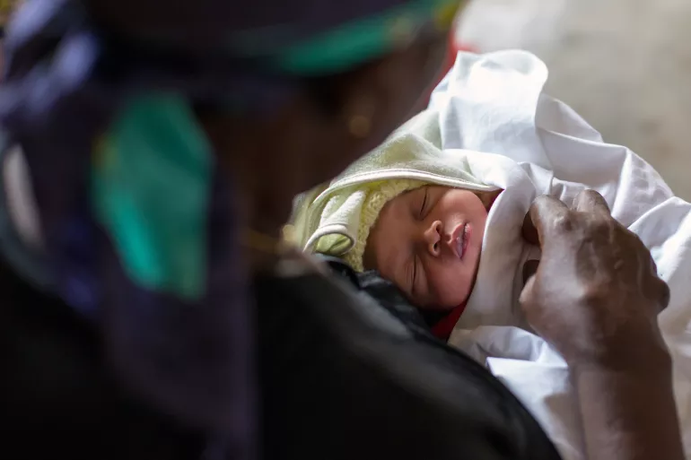 Un b&eacute;b&eacute; dormant dans les bras de sa maman