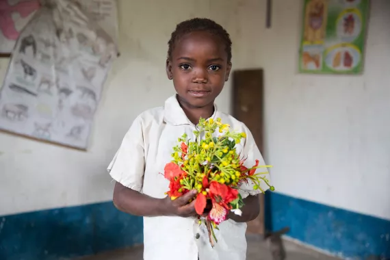 Une fille tenant un bouquet de fleurs dans sa salle de classe