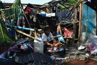 A resident bathes her child next to their destroyed house in Carcar, Philippines
