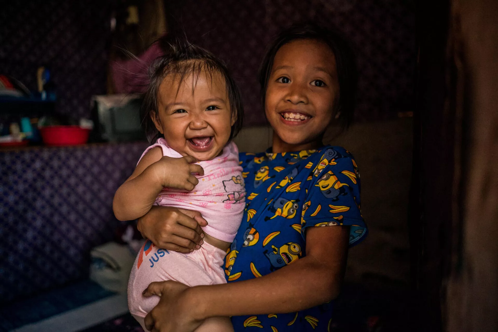 A girl holds her 13-month-old niece Jonaila inside their house. The next day Jonaila will receive her first vaccines.