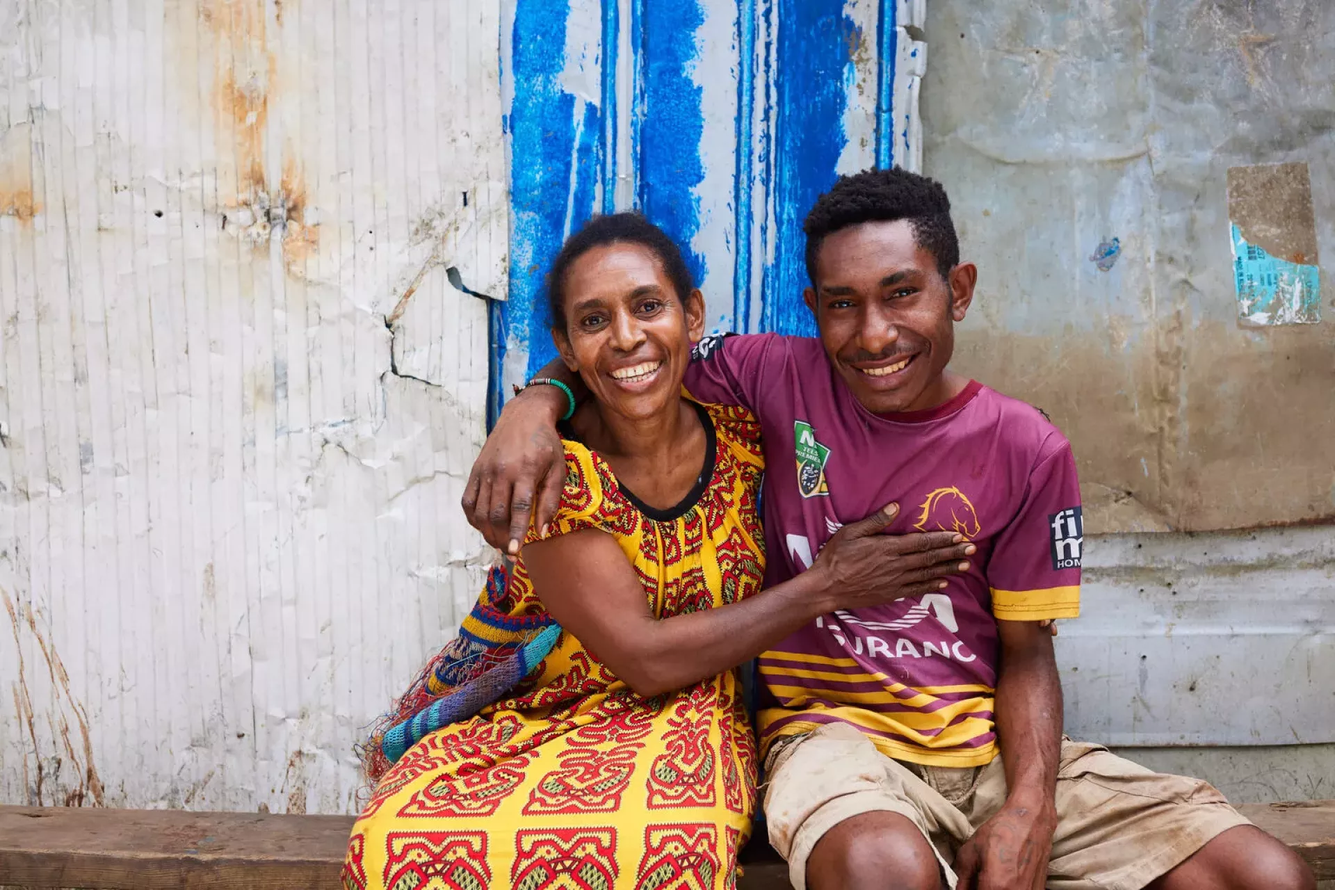 A smiling teenager with his arm around his mother