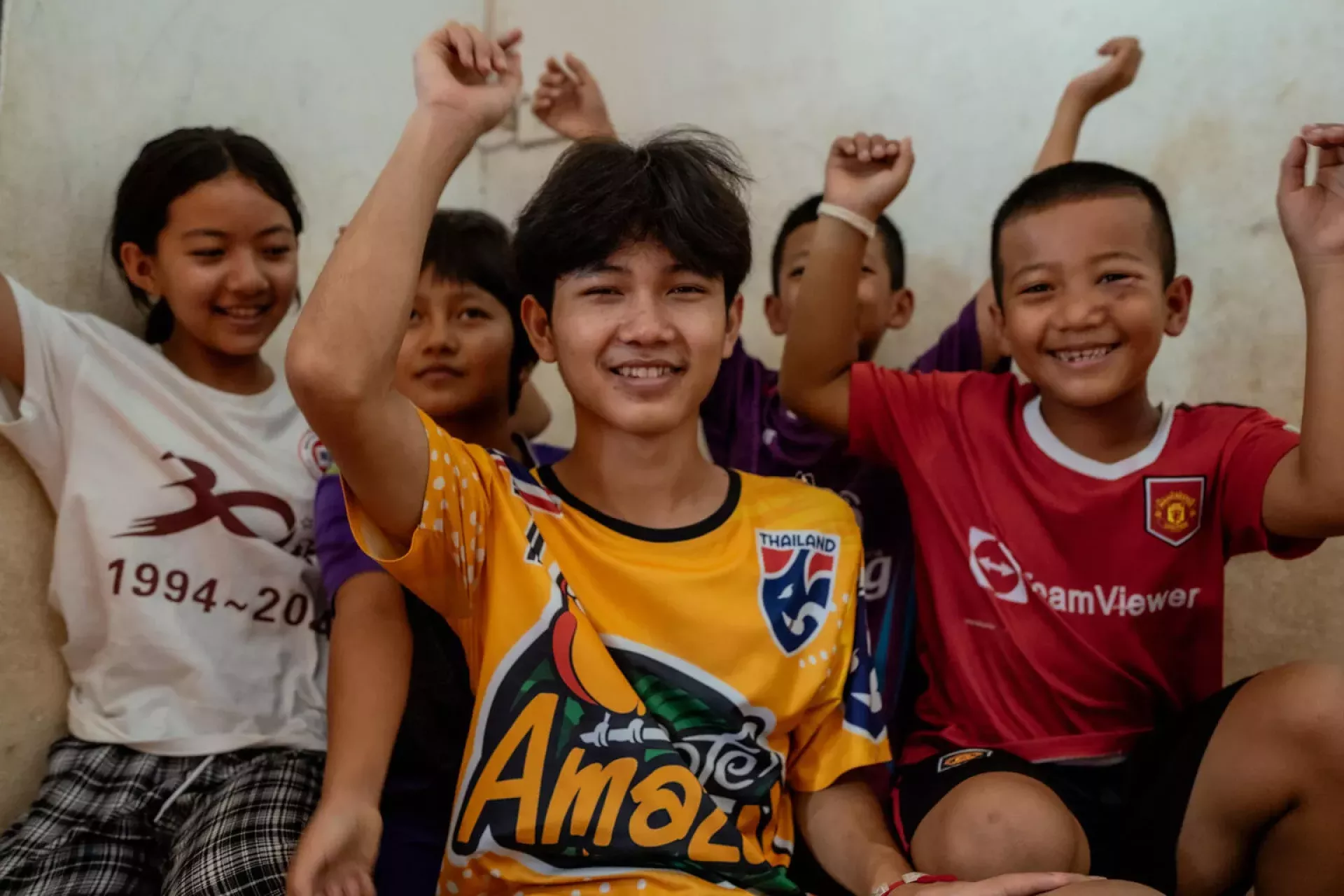 Young boys and girls raising their hands, smiling at the camera
