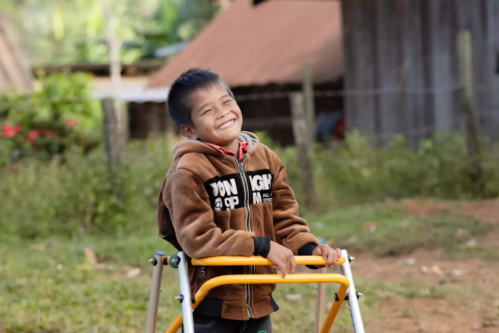 A boy with an assistive walker smiles