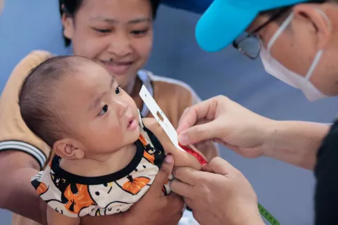 Adrian Villegas, Nutrition Officer at UNICEF Philippines, checks the nutritional status of 8-month-old Hadzmher using a Mid-Upper Arm Circumference (MUAC) tape to measure if a child has acute malnutrition