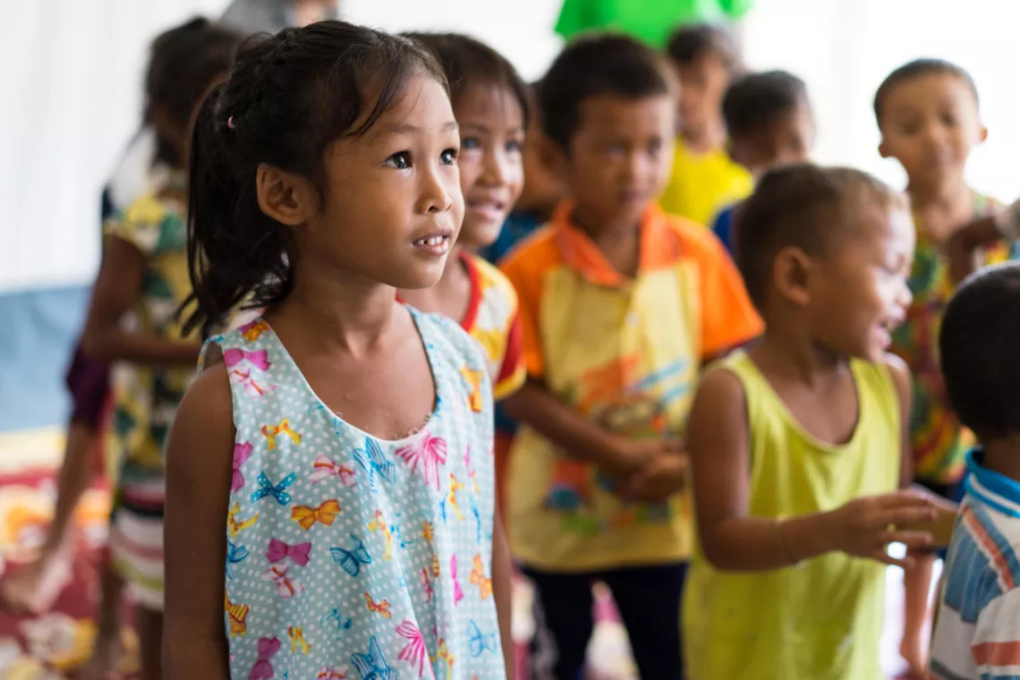 A girl smiles and looks at a volunteer teacher in a class activity in a Child Friendly Space in Ban Bok camp, Attapeu, Lao PDR