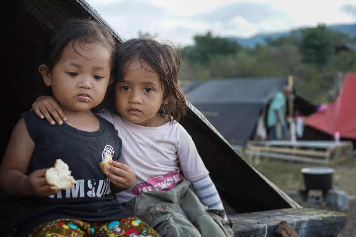 Two girls sitting on the grass. They are displaced due to a a tsunami triggered by a 7.4 magnitude earthquake off the coast of Sulawesi, Indonesia