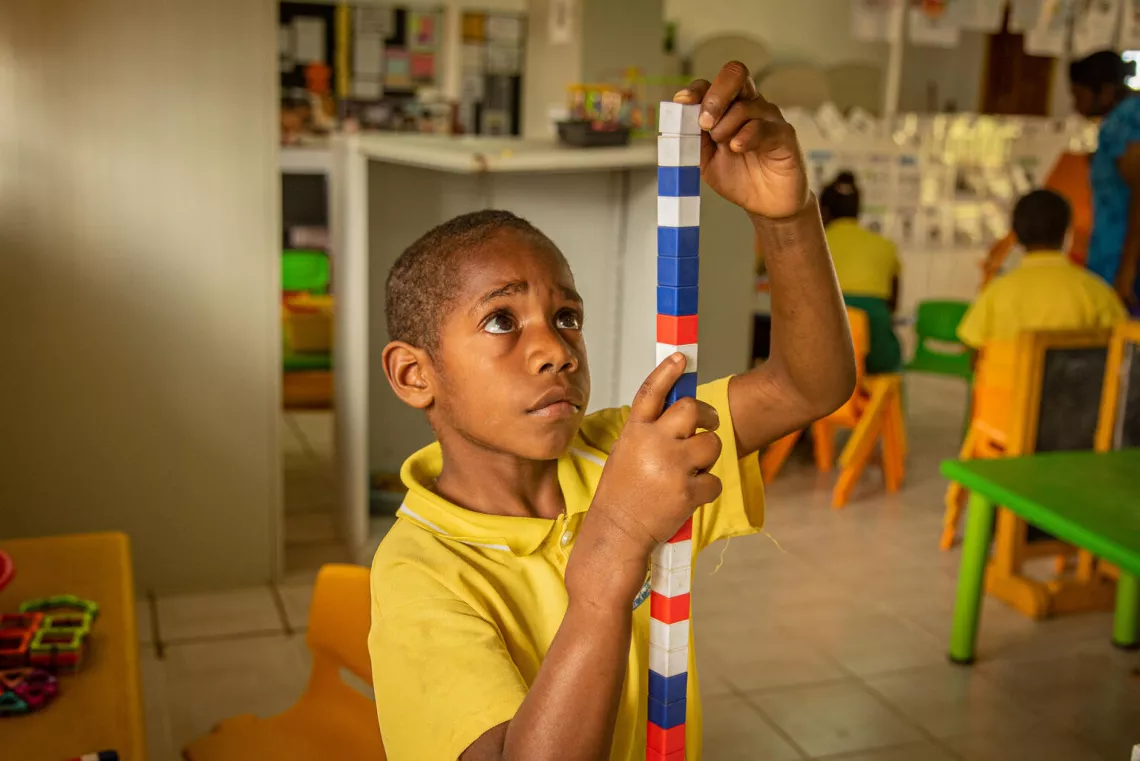 A child living with disability, plays with instructive toys in the inclusive education classroom at school in Vanuatu