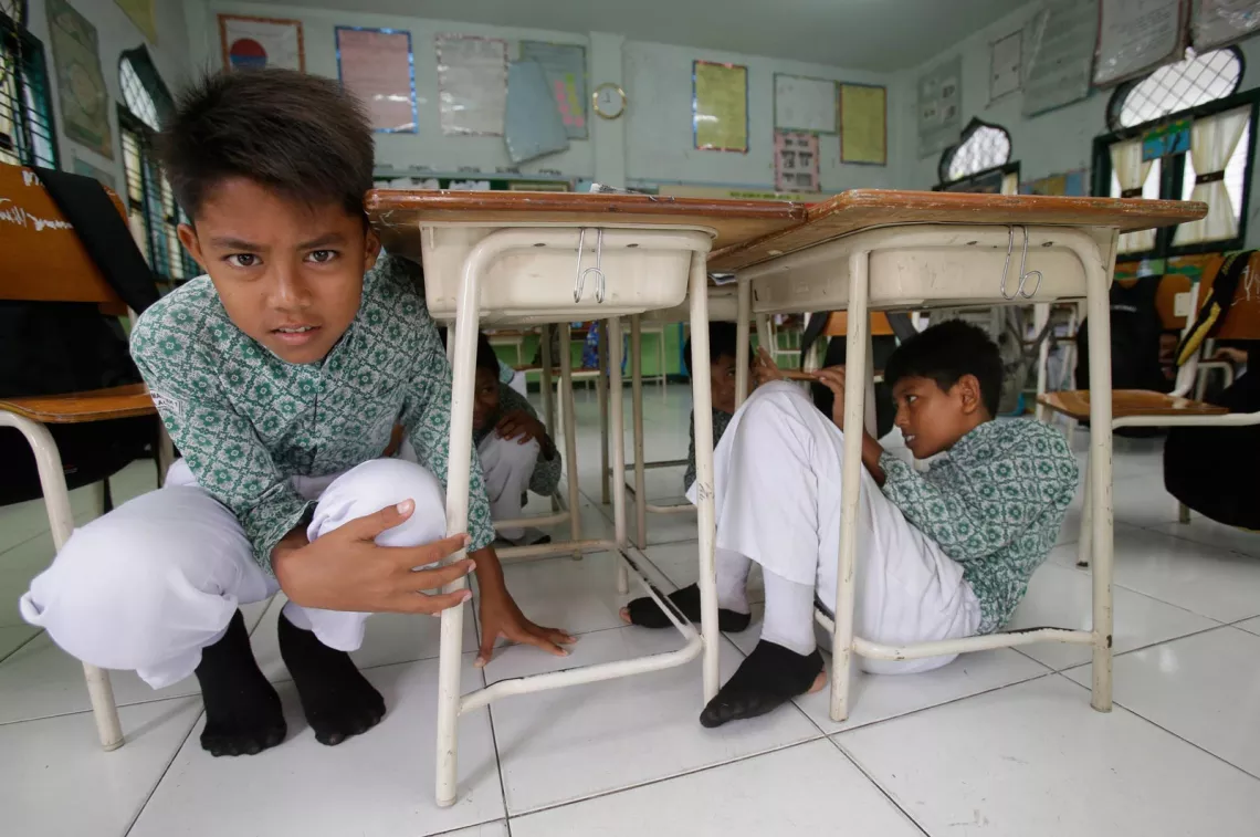 Students sit under a table during an earthquake drill at Muhammadiyah 1 Primary school in Banda Aceh,Indonesia