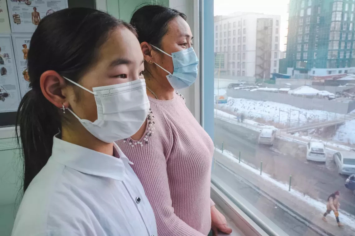 Gantsetseg Erdenebayar and her teenage daughter, Temuunzaya, look out at the air pollution in Ulaanbaatar, Mongolia from a hospital window