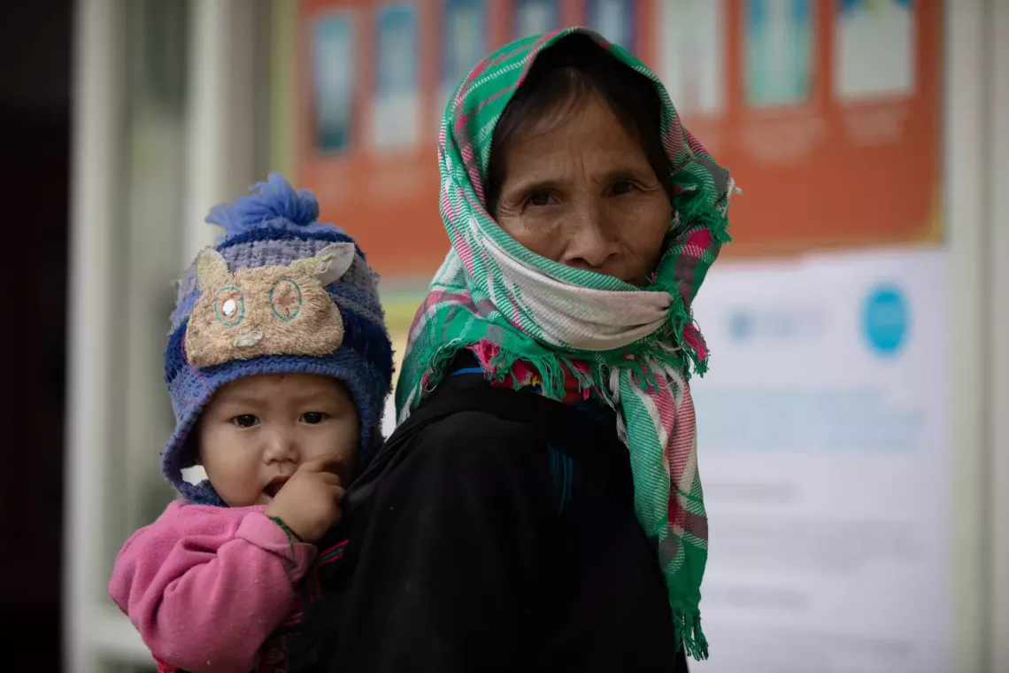 57-year-old Lam Thi Chanh, a Tay ethnic minority grandmother, and her 18-month-old grandson, Vang A Binh, in registering for UNICEF's cash assistance program