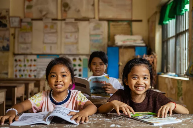Three students read their workbooks in the classroom