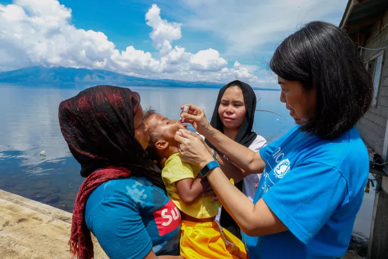 Dr. Sally Bataclan, Health & Nutrition Specialist of UNICEF Philippines, gives anti-polio vaccine to a child in Lumbatan, Lanao del Sur, during a polio vaccination campaign