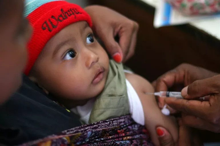 A health worker vaccinates a toddler against measles, Indonesia