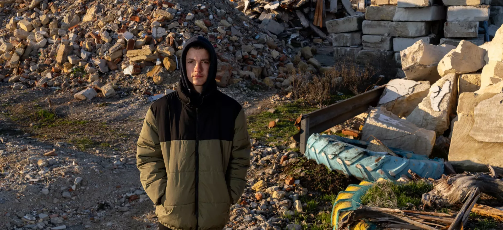 A boy stands in front of his destroyed school