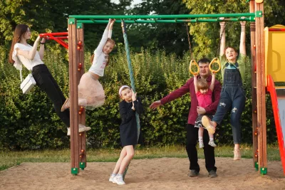 A father plays with his children outside. 