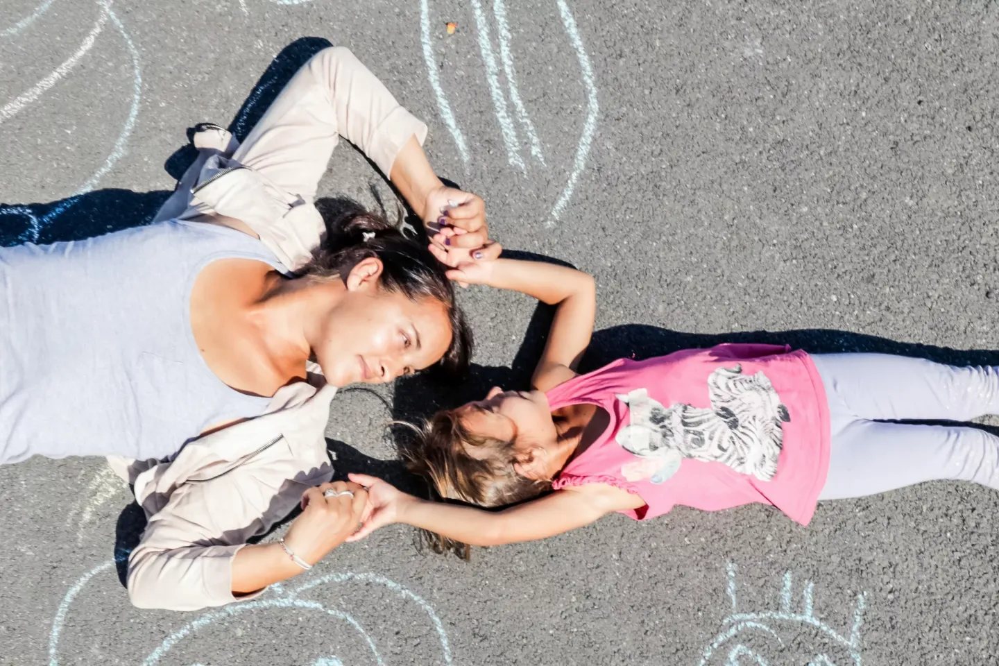 Mother and daughter lay on the ground next to chalk artwork