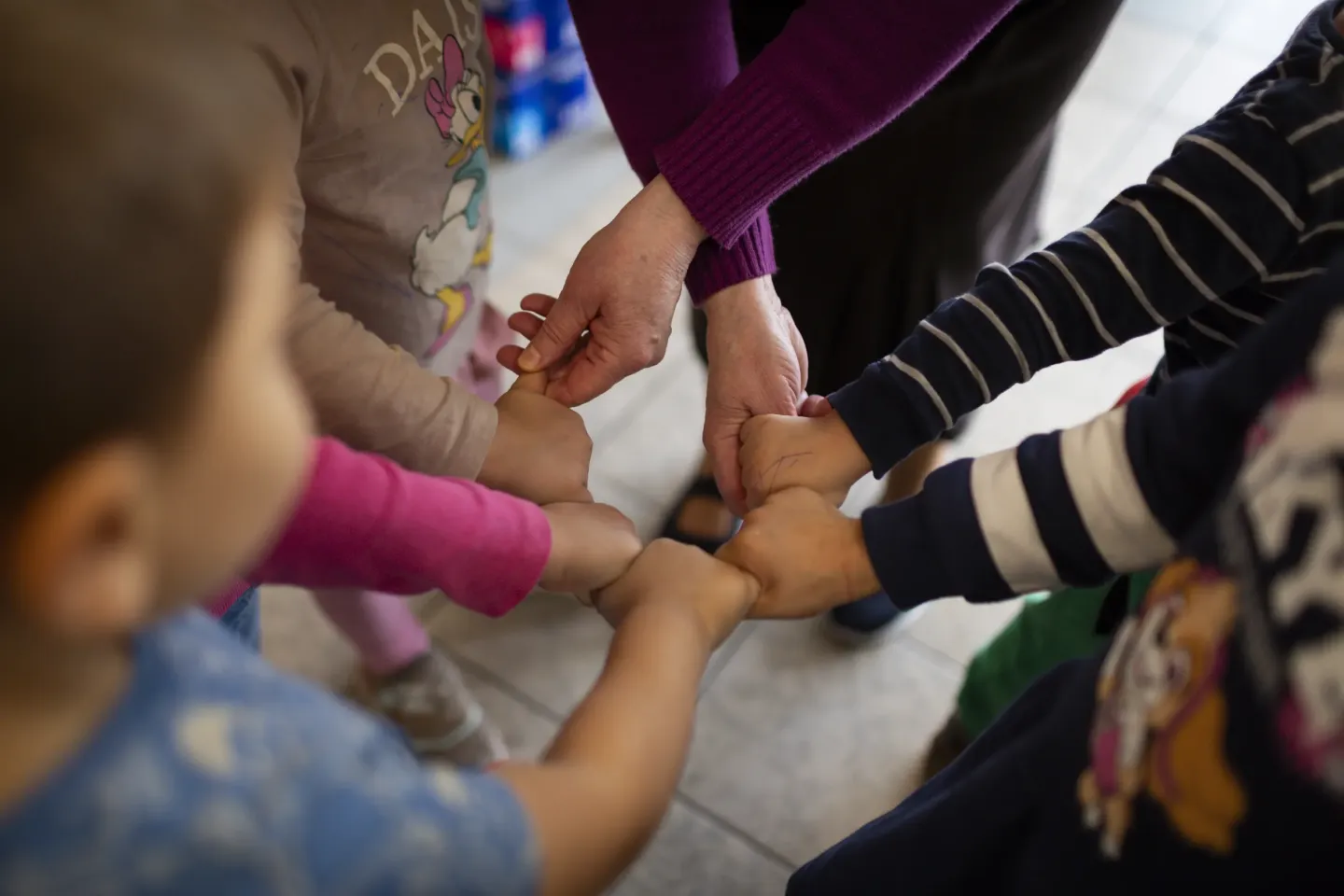 Lidiia Shulha and children at the collective center for refugees in Soczewka, Mazowieckie Voivodeship, hold hands after class &mdash; a daily ritual that ends their learning together.
