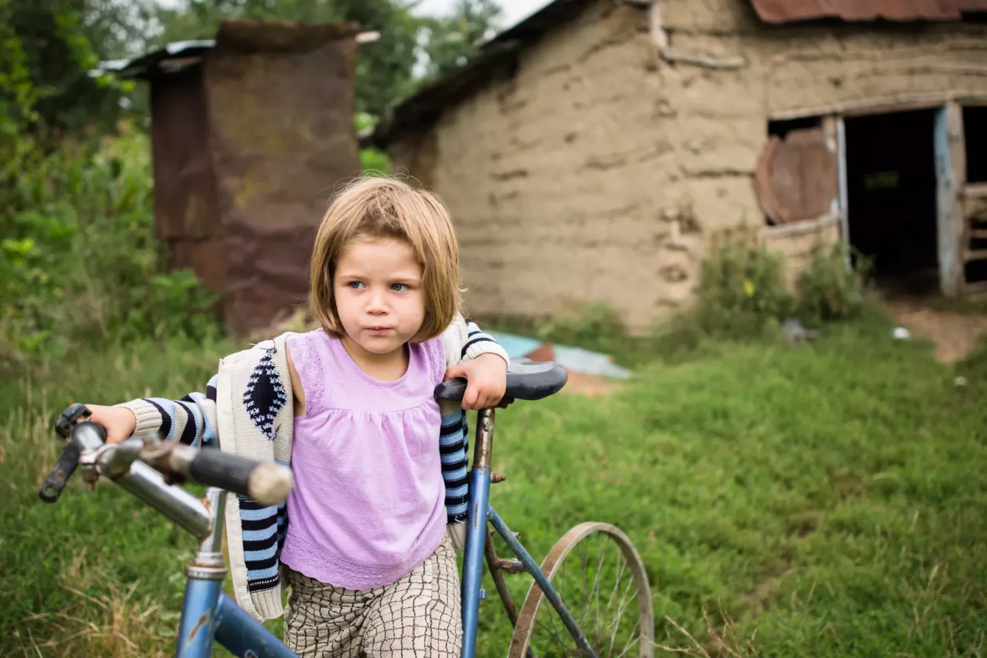 A girl stands by her bicycle. 