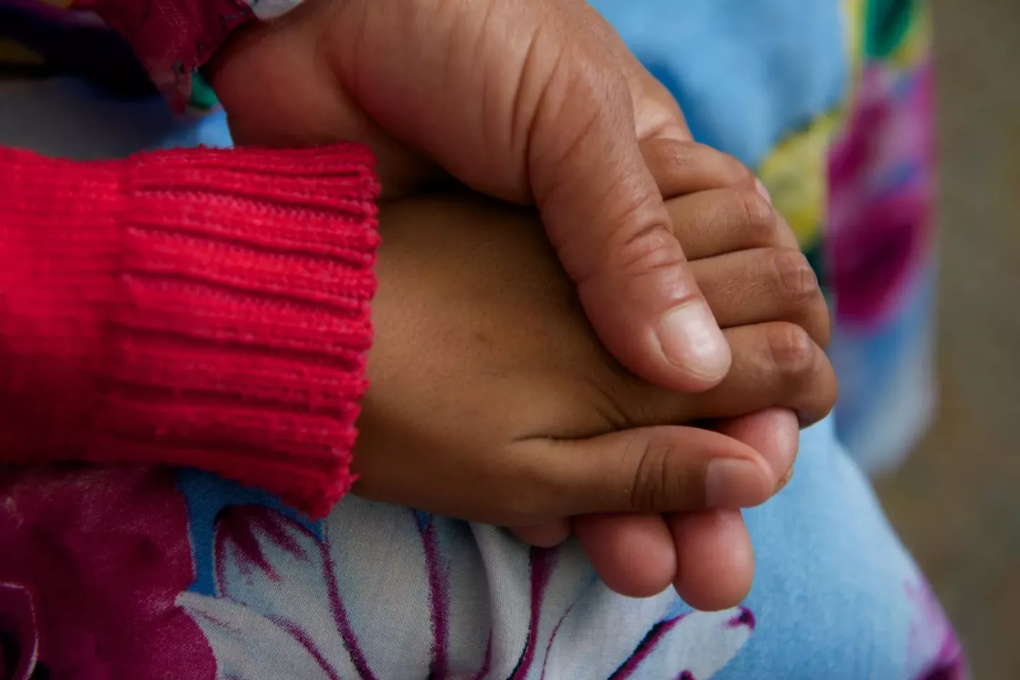 A man holds hands of his daughter, a young girl child.