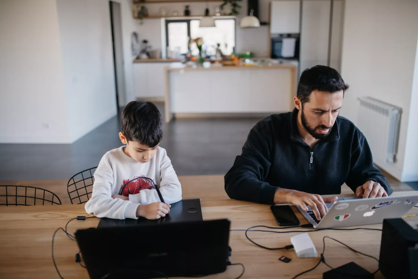 A boy and his father work on computers next to each other