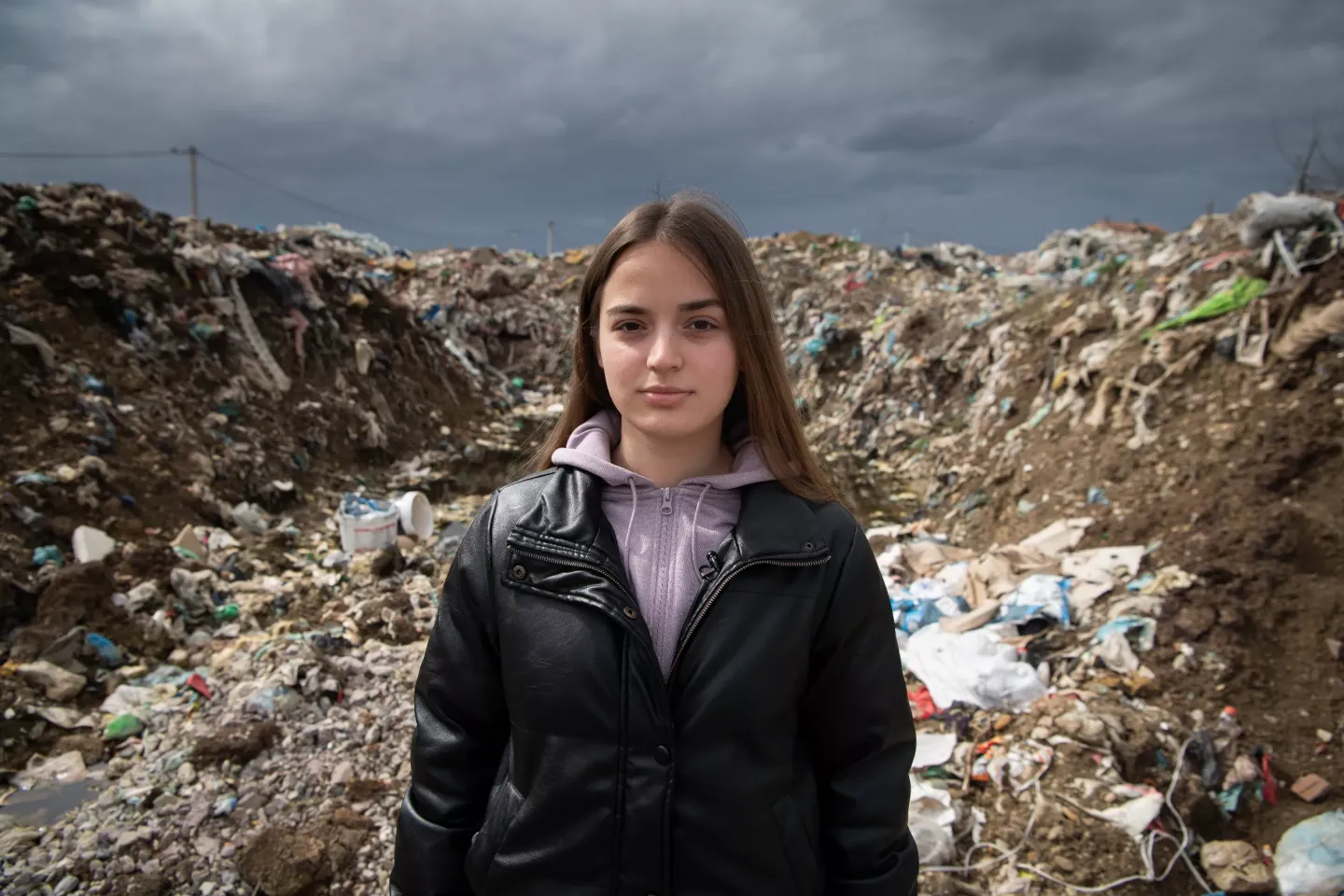 Sara stands in front of a landfill in Kolonia District in the city of Gjakova, Kosovo.