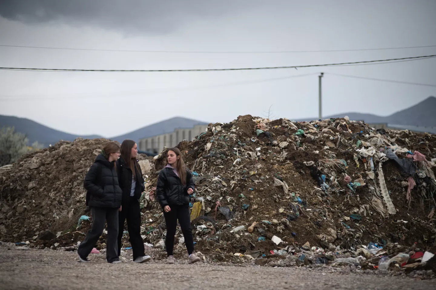 Young activists walk in front of discarded trash in landfull near their homes in Kolonia District in the city of Gjakova, Kosovo.