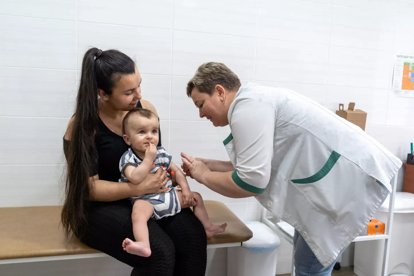 Eight-month-old Orest is in his mother's hands, waiting for vaccination next to the nurse Tetiana, at the health centre in Kyiv's Shevchenkivskyi district.