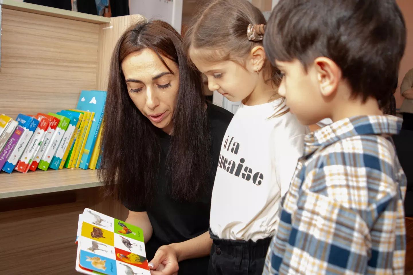 A teacher reads a book to two children. Georgian language teacher at Akhalkalaki Kindergarten #2, participant in the bilingual education project of UNICEF and the Estonian Centre for International Development.