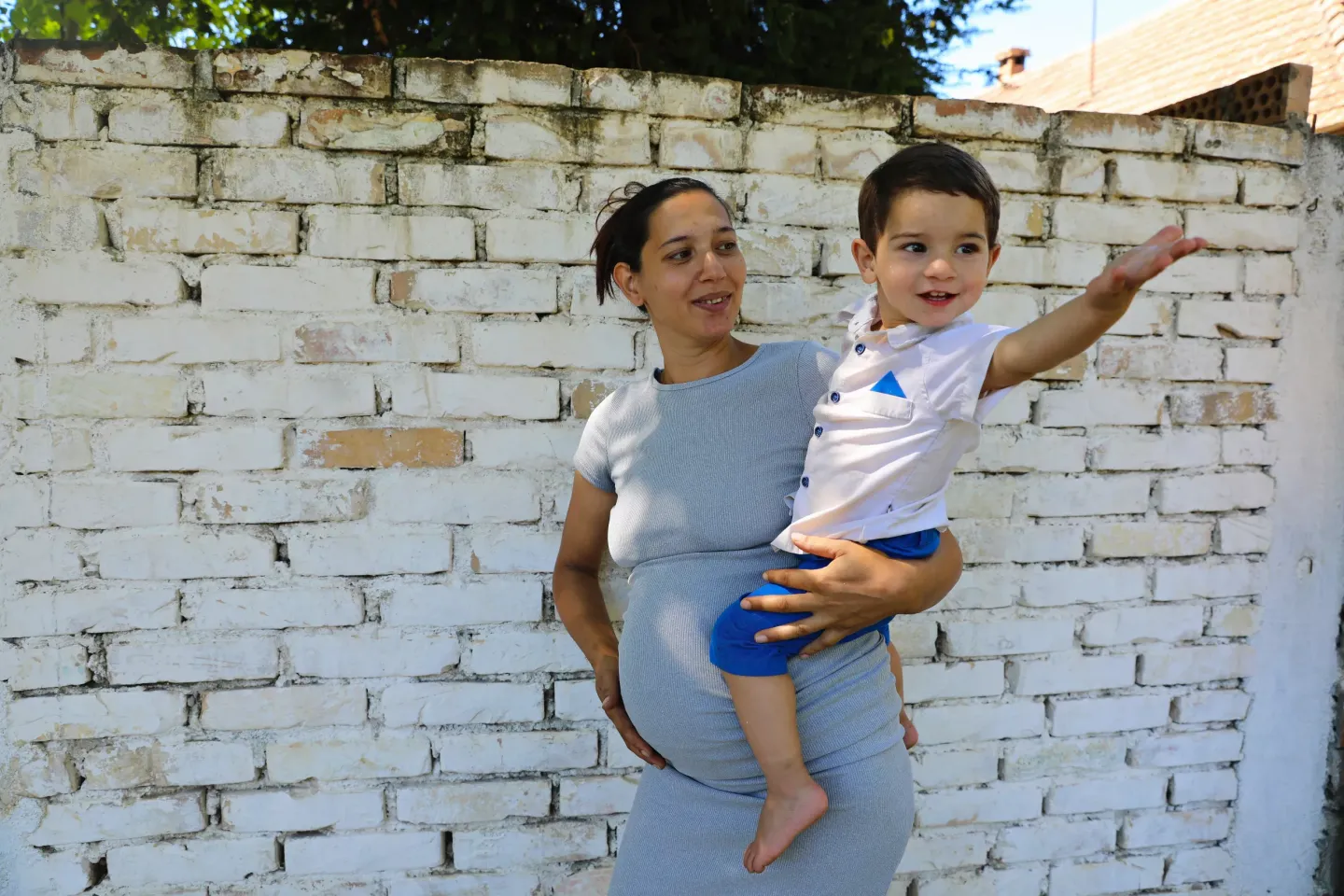 A pregnant Roma woman holding her youngest child in her home in Vrsac, Serbia, during the visit of the home visiting nurse.