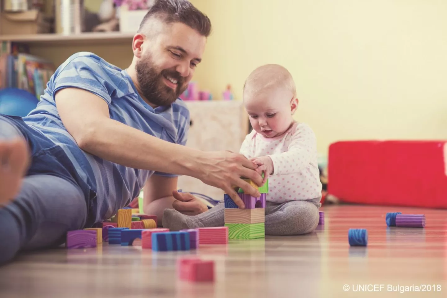 Father playing with child with toy bricks.