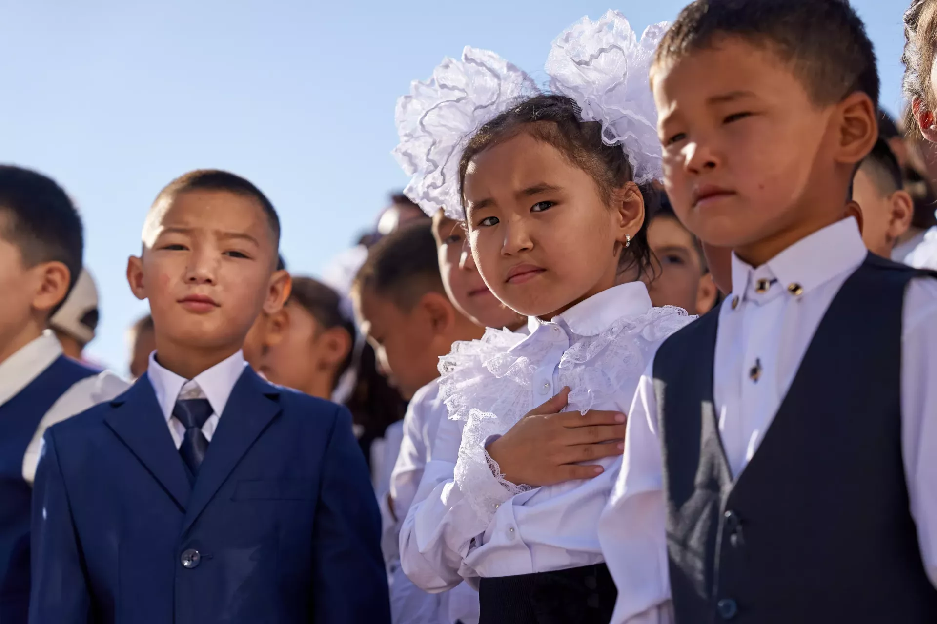 First grader in Kyrgyzstan holding her hand next to her heart as the country hymn plays.