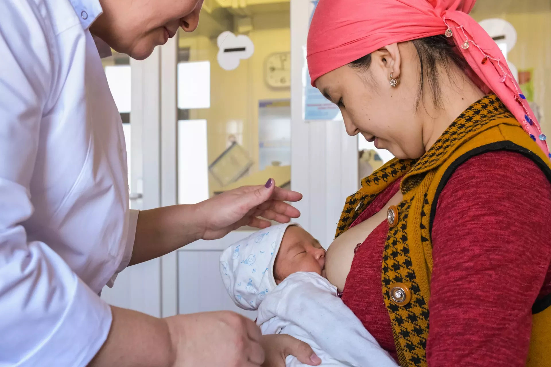 An obstetrician of neonatal ward helping mother to breastfeed