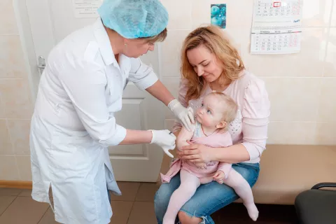 Дана, 1,3 года, которую держит ее мать Инна, не плачет, когда ей вводят первую дозу вакцины против эпидемического паротита, кори и краснухи (MMR) 4 апреля 2018 года в детской поликлинике №1 Оболонского района, Киев, Украина.