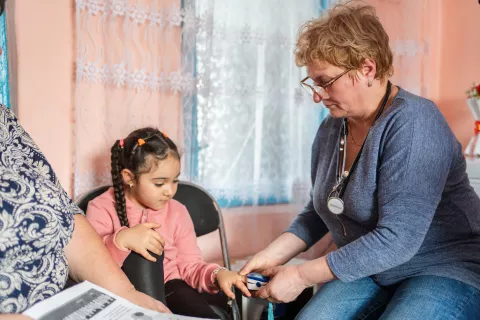 Five-year-old Antonia has her pulse and oxygen saturation level measured during a medical check-up by community nurse.