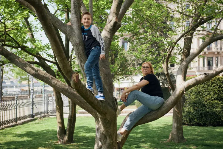 Mother and son climb a tree. 