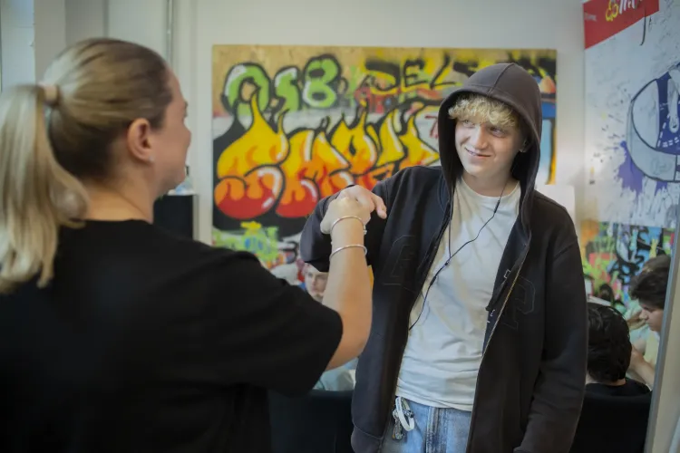 The image shows a 15-year old Artem with the youth worker in a youth club.