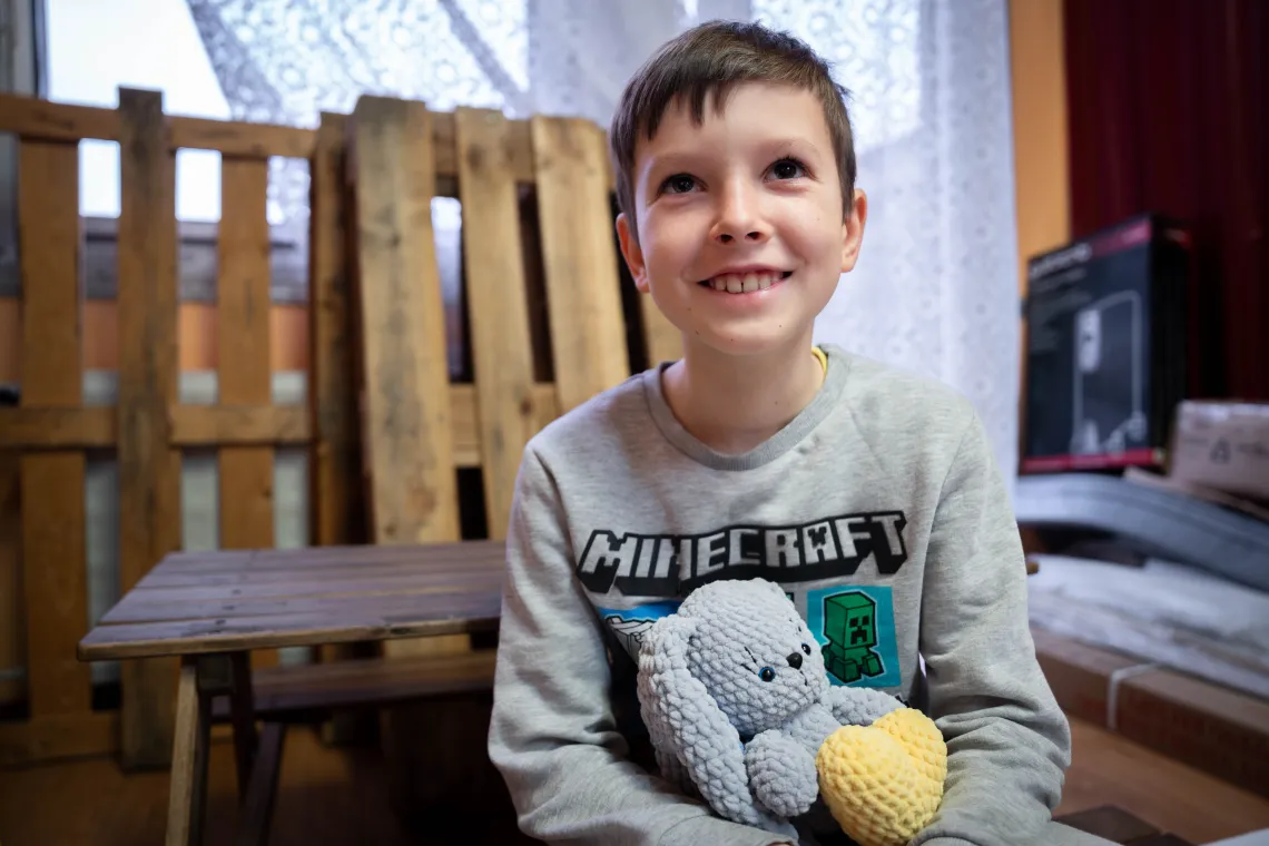 Denis smiles as he holds its toy bunny.