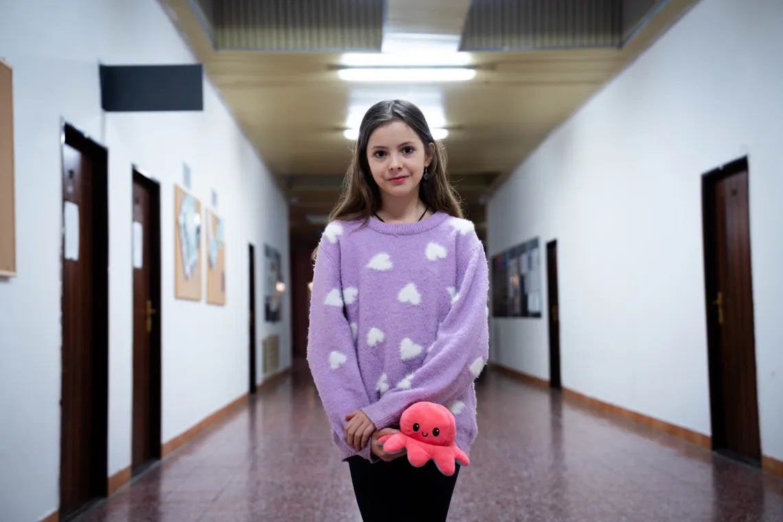 Vika stands in a hallway, octopus toy in her hand.