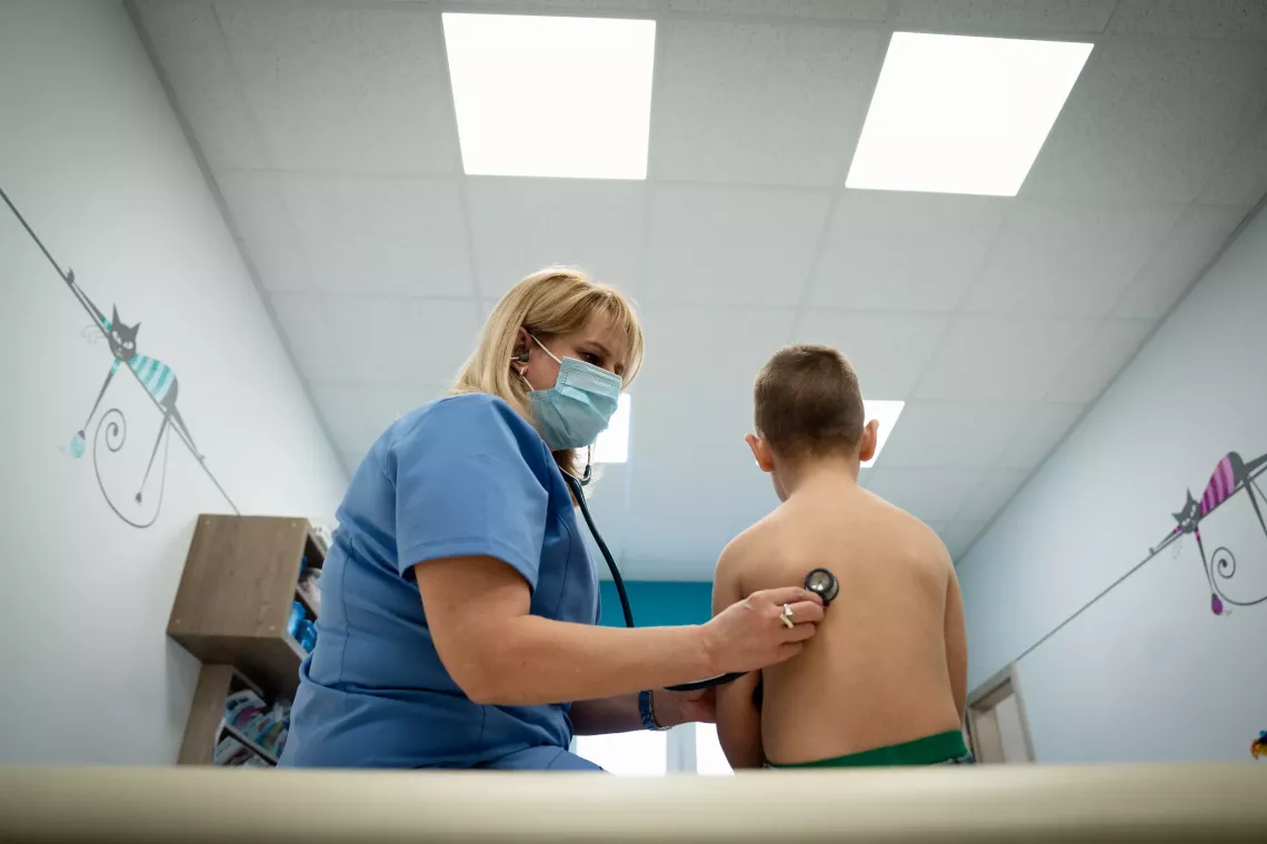 Tatiana, a Ukrainian pediatrician, examines her young patient with a stethoscope.